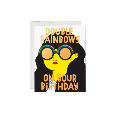 Cartoon woman wearing double rainbow sunglasses, says "Double Rainbows On Your Birthday".This 5.5 x 4.25 inch Double Rainbows Birthday Card is printed on 100lb heavyweight card stock and features a foil stamped, offset printed illustration by Anke Weckmann. It is printed in the USA on recycled paper and is blank inside.