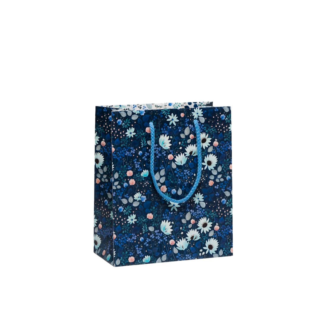 Floral print on black background, blue rope handle.A Small Size Northern Currants Gift Bag measures 8x4x9.5 inches, constructed from heavyweight coated paper and equipped with a cotton rope handle. The bag is illustrated by Anna Emilia Laitinen.
