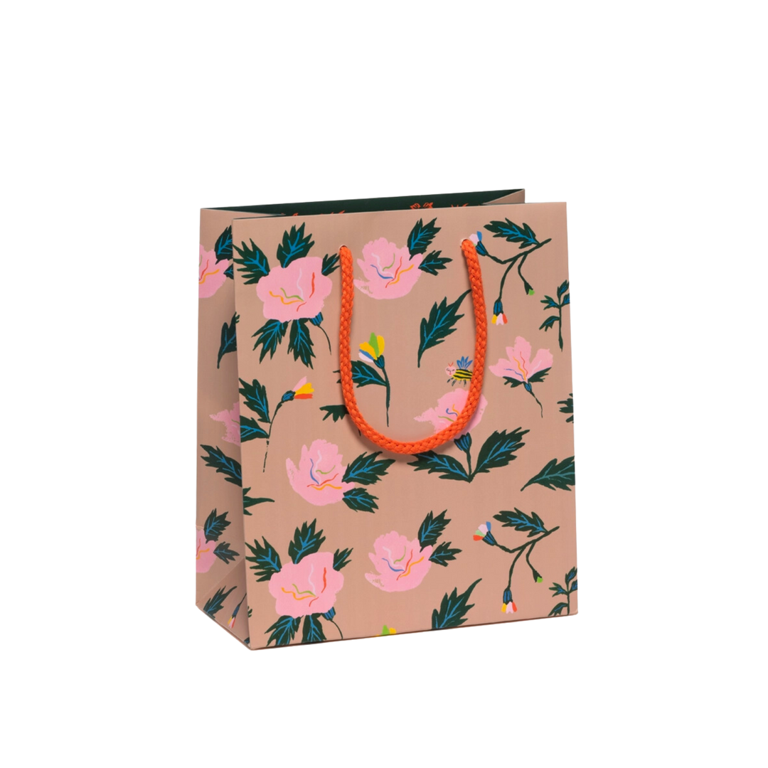 Pink roses with green leaves on a brown background with orange rope. Small Dimensions – 8" x 4" x 9.5". Crafted of Durable Coated Paper. Cotton Rope Handle. Artwork by Emily Isabella